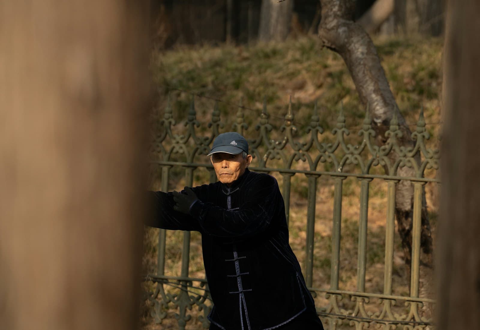 An older adult practicing gentle tai chi movement outdoors
